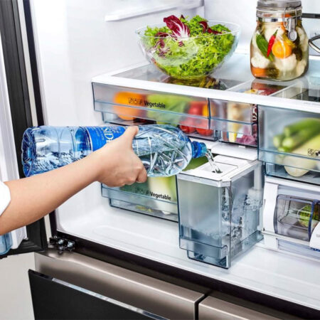 Hand schenkt water in de lade van de Hitachi R-WB640VRU0 Amerikaanse koelkast.